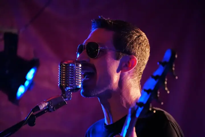 Chanteur au micro sur scène, lumières de concert
