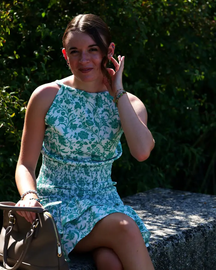 Portrait de Célia, à Dijon : assise sur un muret, en robe à fleurs